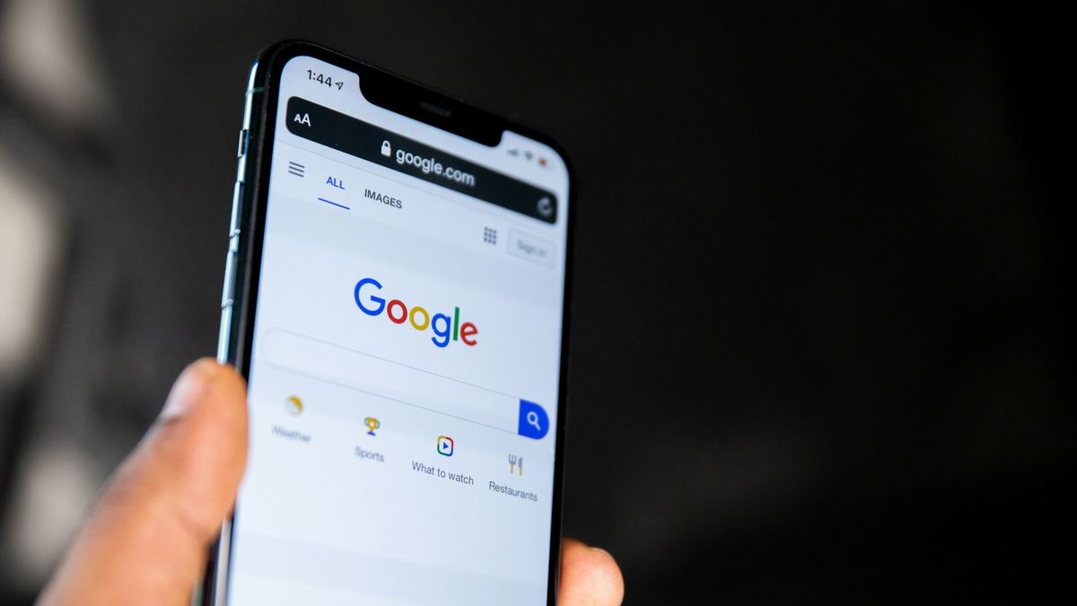 Mano sosteniendo un móvil con la página de inicio de Google abierta