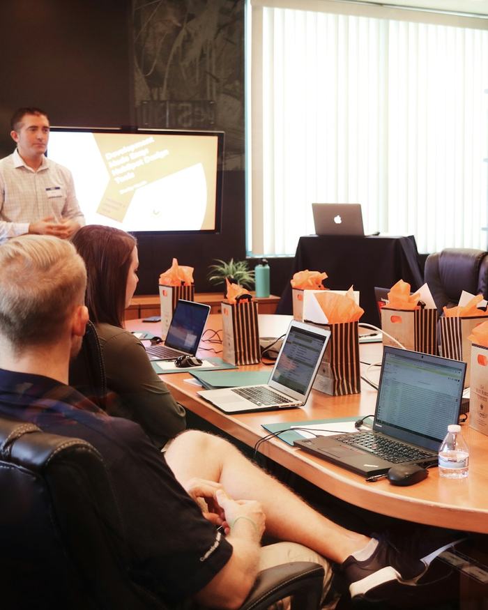 Formador de pie explicando SEO ante un grupo con portátiles en una sala de formación