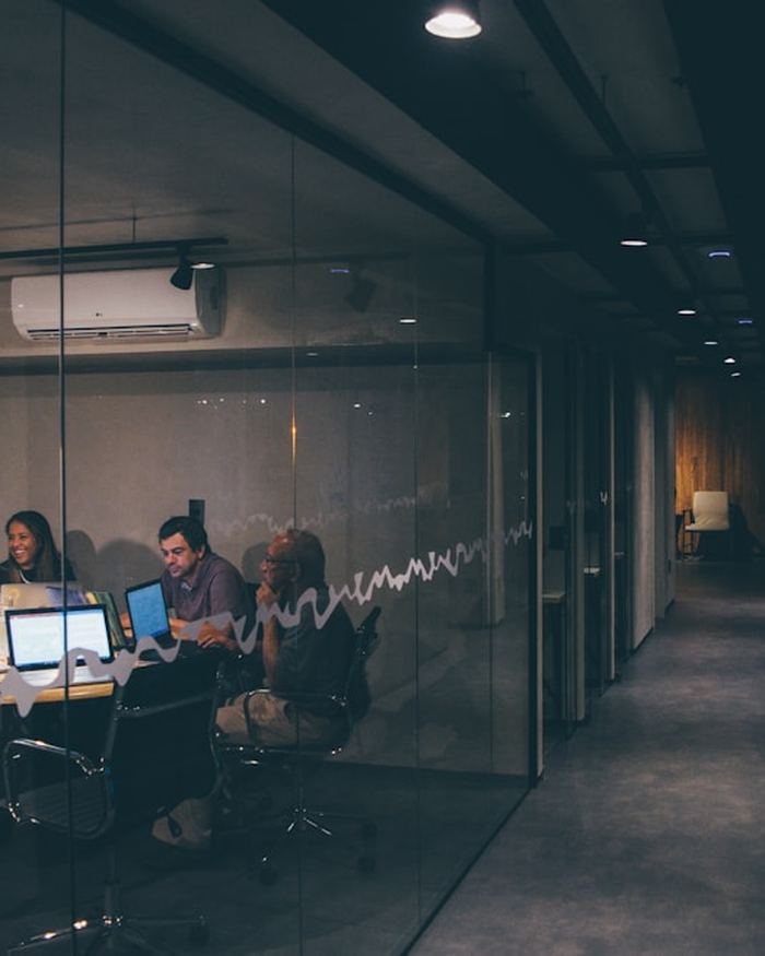 Reunión de equipo en una sala de agencia por la noche, con datos en pantalla